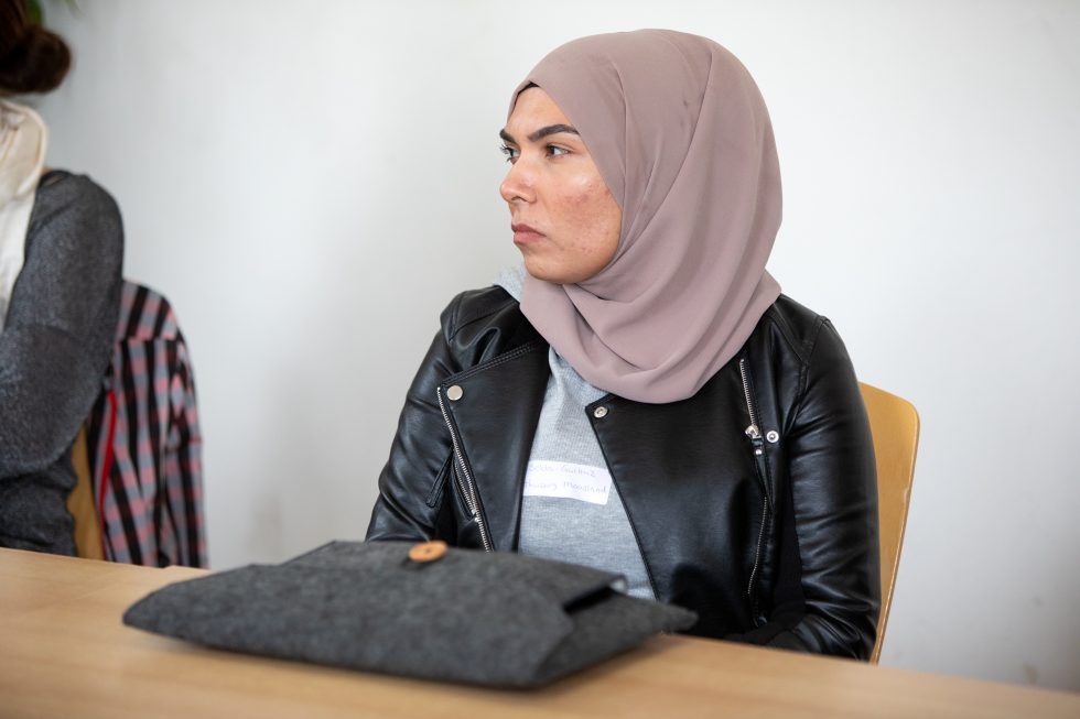 Een persoon zit aan een tafel en luistert aandachtig.