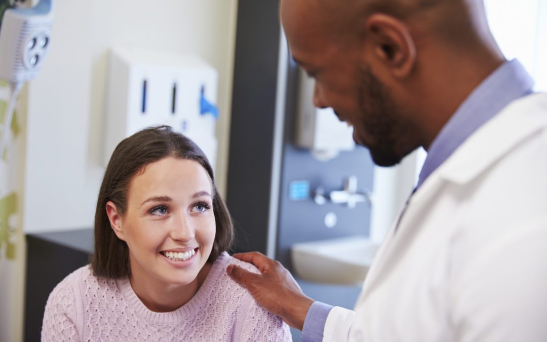 Een vrouw kijkt glimlachend naar haar dokter.