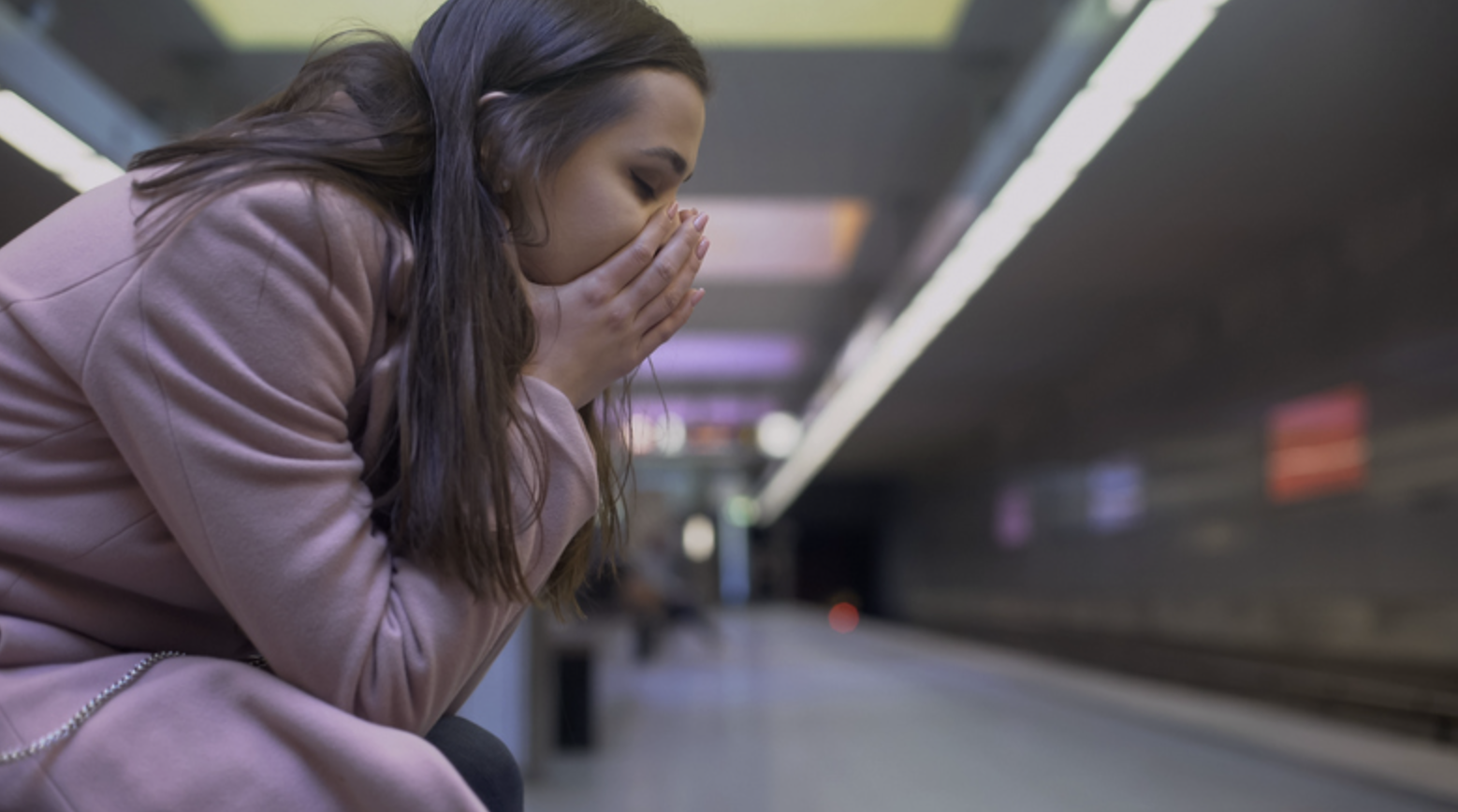 Een vrouw kijkt bedroefd voor zich uit en zit op een bankje.