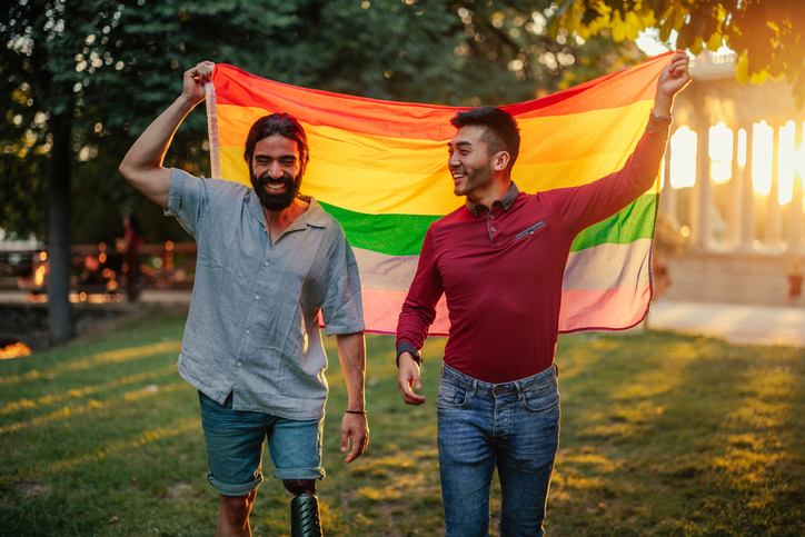 Twee mannen houden de regenboogvlag vast.