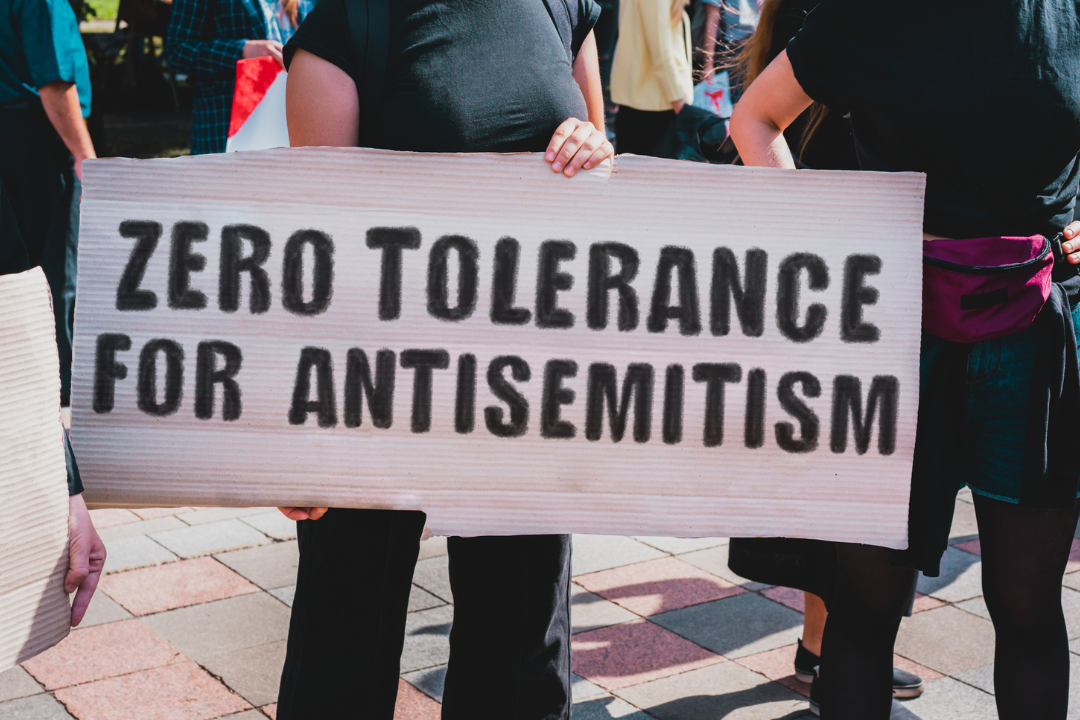 De tekst "Zero tolerance for antisemitism" staat op een kartonnen bord geschreven. Een meisje houdt het bord met de boodschap omhoog. Meisjes op straat. Protest, demonstratie. Rally.