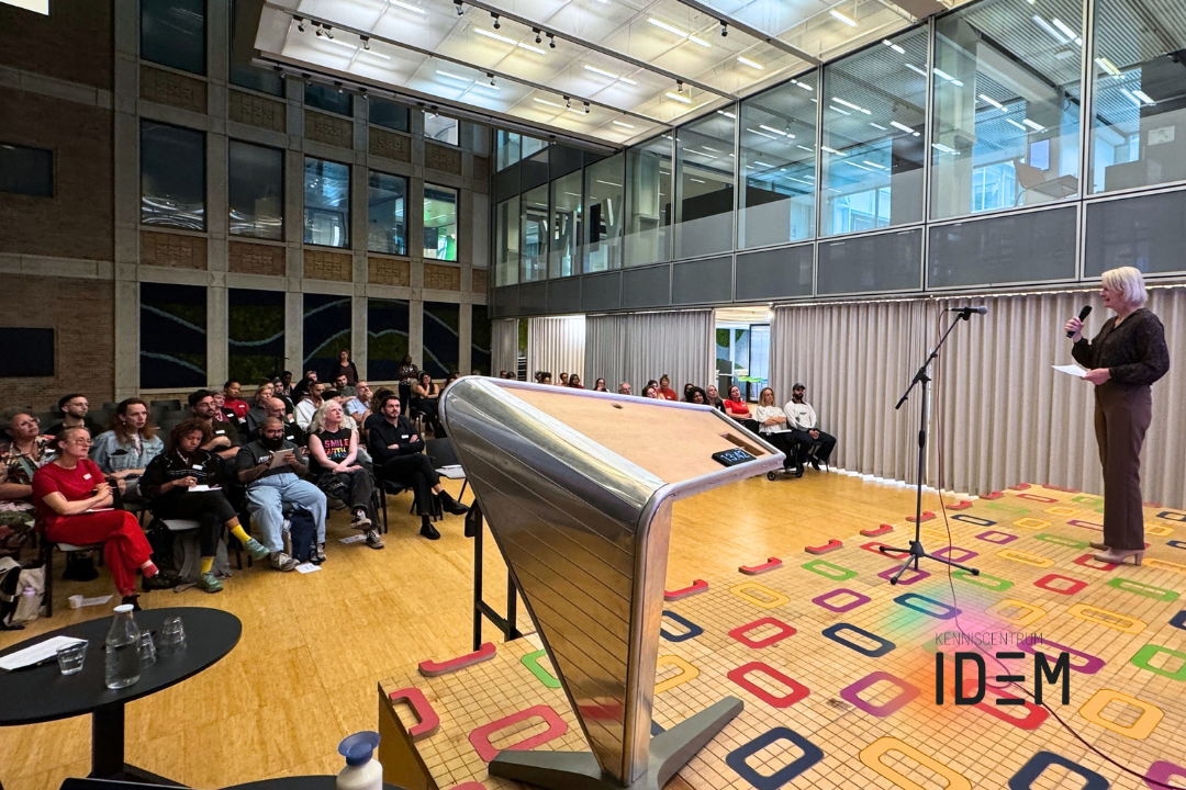 Pride in de Praktijk-conferentie met dagvoorzitter Lisa van Ginneken die het publiek welkom heet.